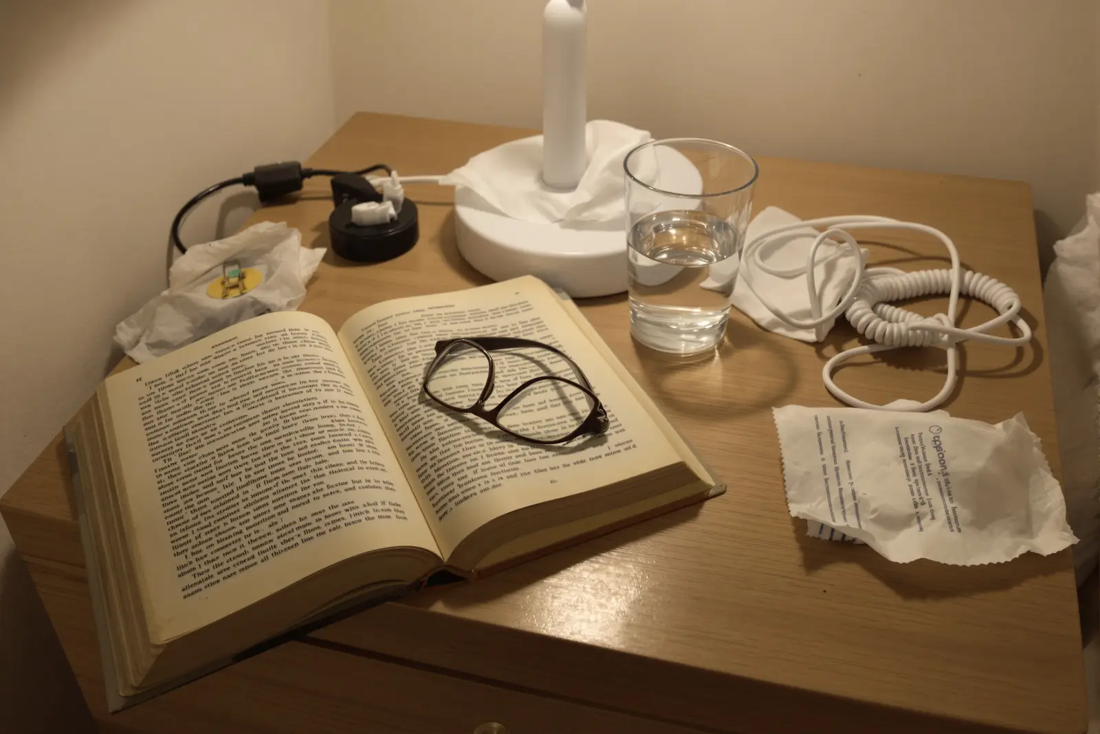 Aufgeschlagenes Buch im warmen Licht der Nachttischlampe: die Abendroutine als Rampe in den Schlaf