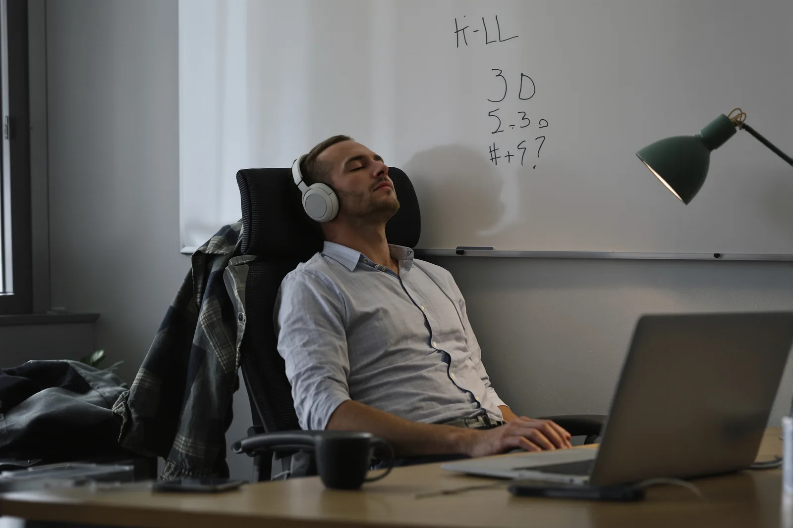 Unternehmer bei einer Selbsthypnose-Session am Schreibtisch mit geschlossenen Augen und Kopfhörern. Schritt für Schritt der Business Hypnose