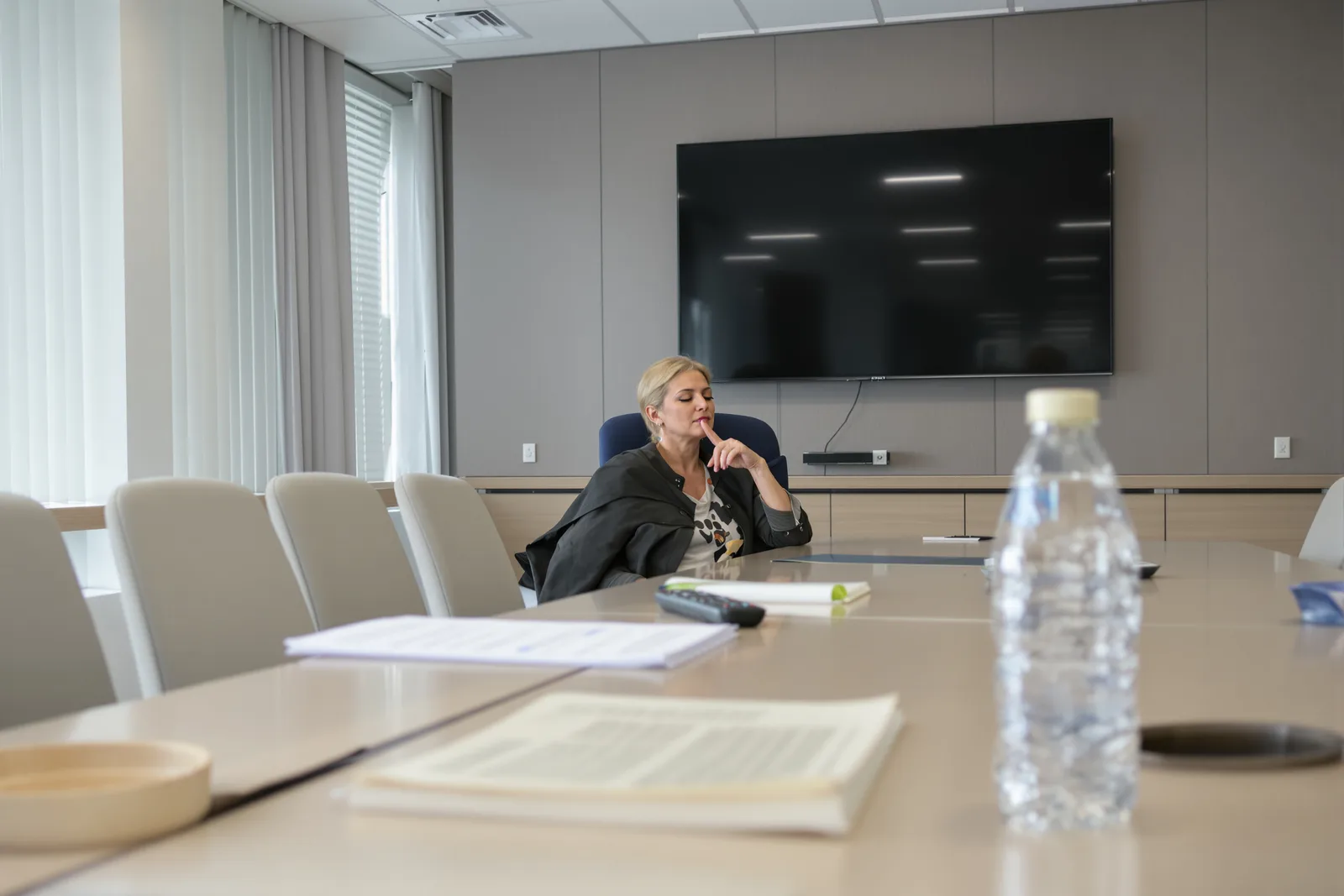 Managerin übt vor dem Board-Termin allein im leeren Besprechungsraum ihren Ruhe-Anker. Schritt für Schritt der Hypnose für Führungskräfte