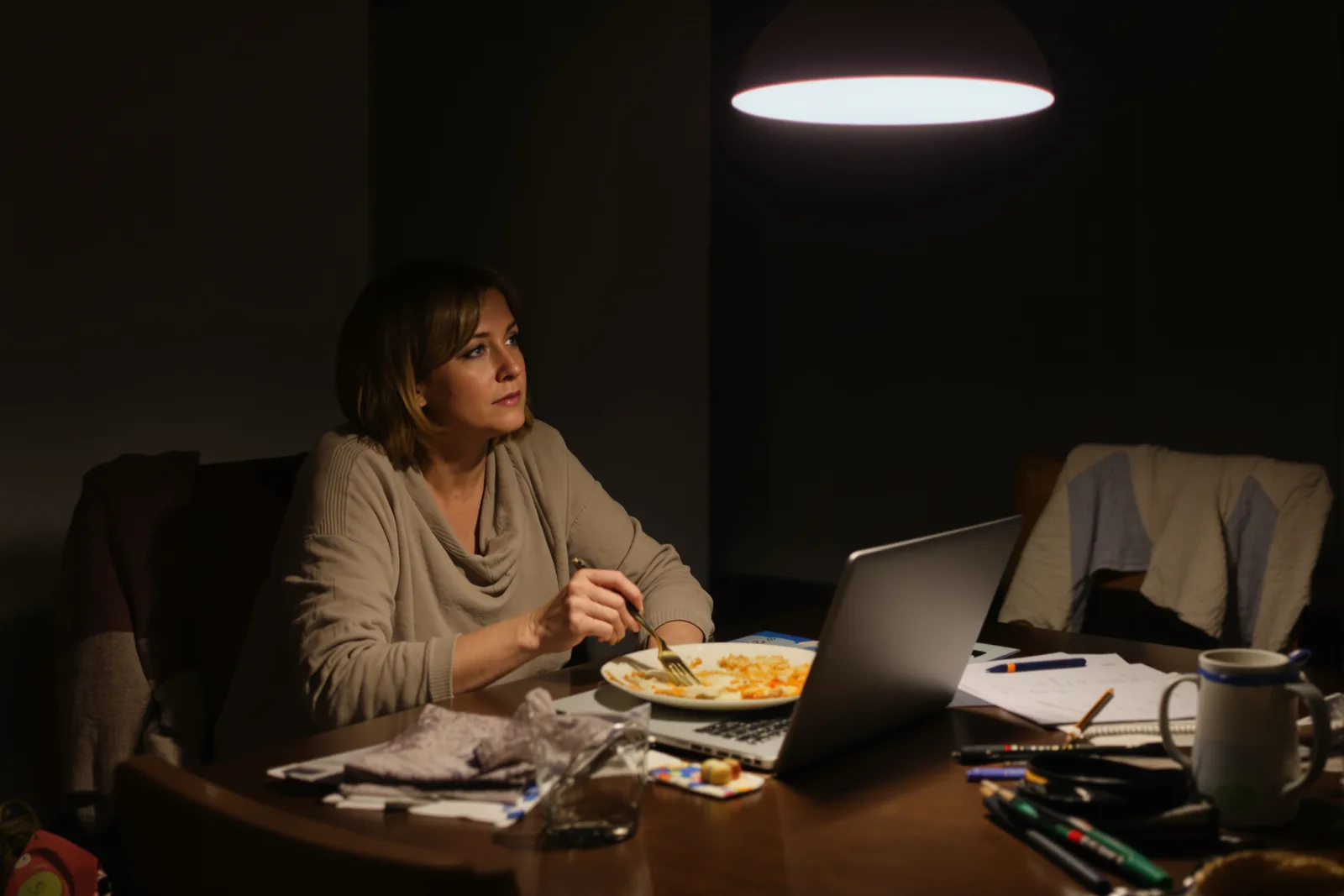 Mann lehnt abends an der Küchenarbeitsplatte, in Gedanken: nicht abschalten können nach Feierabend