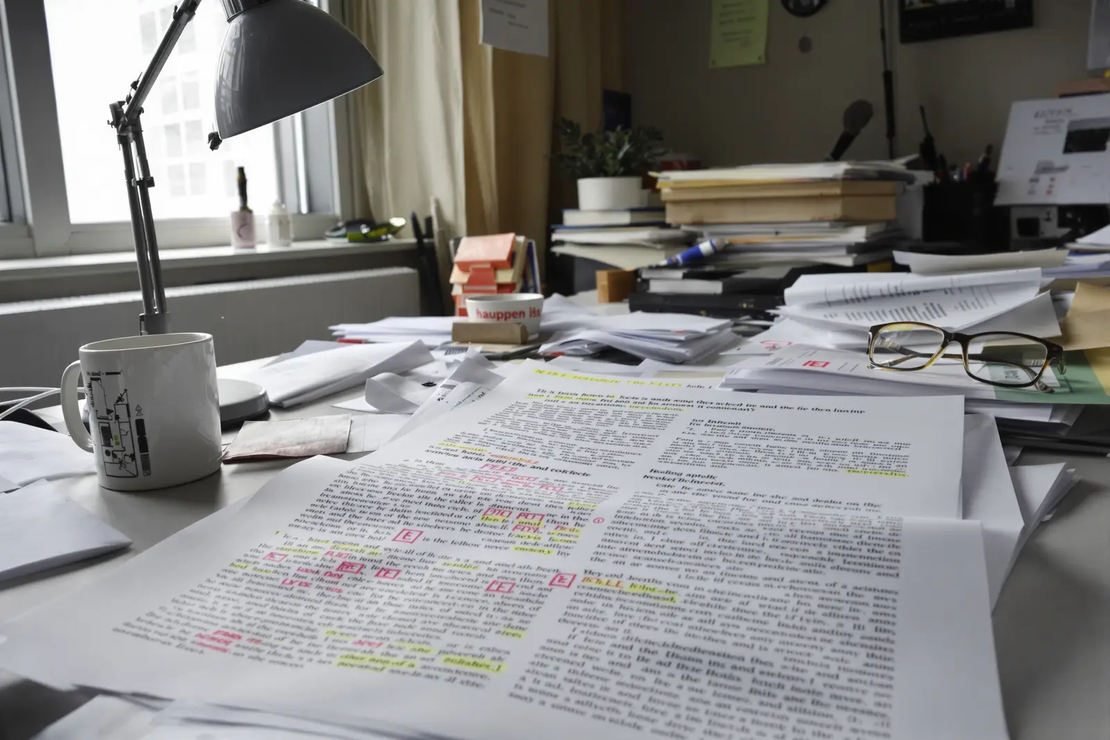 Stapel gelesener Fachjournale mit Lesebrille im warmen Licht einer Schreibtischlampe, die Studienbasis hinter Epiqone